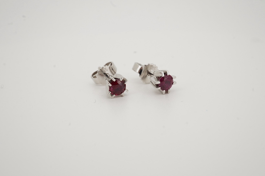 A modern pair of 585 white metal and solitaire ruby set ear studs, overall diameter 5mm, gross weight 1.4 grams. Condition - good